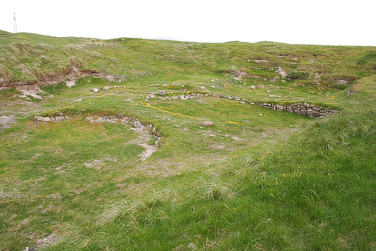 Green field with stone outlines of oval structures.