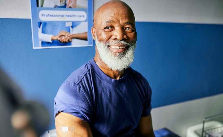 Happy black man with plaster on arm for flu vaccine, illness prevention and virus protection at medical clinic. Senior patient smiling in hospital after injection for immunity, healthcare and safety