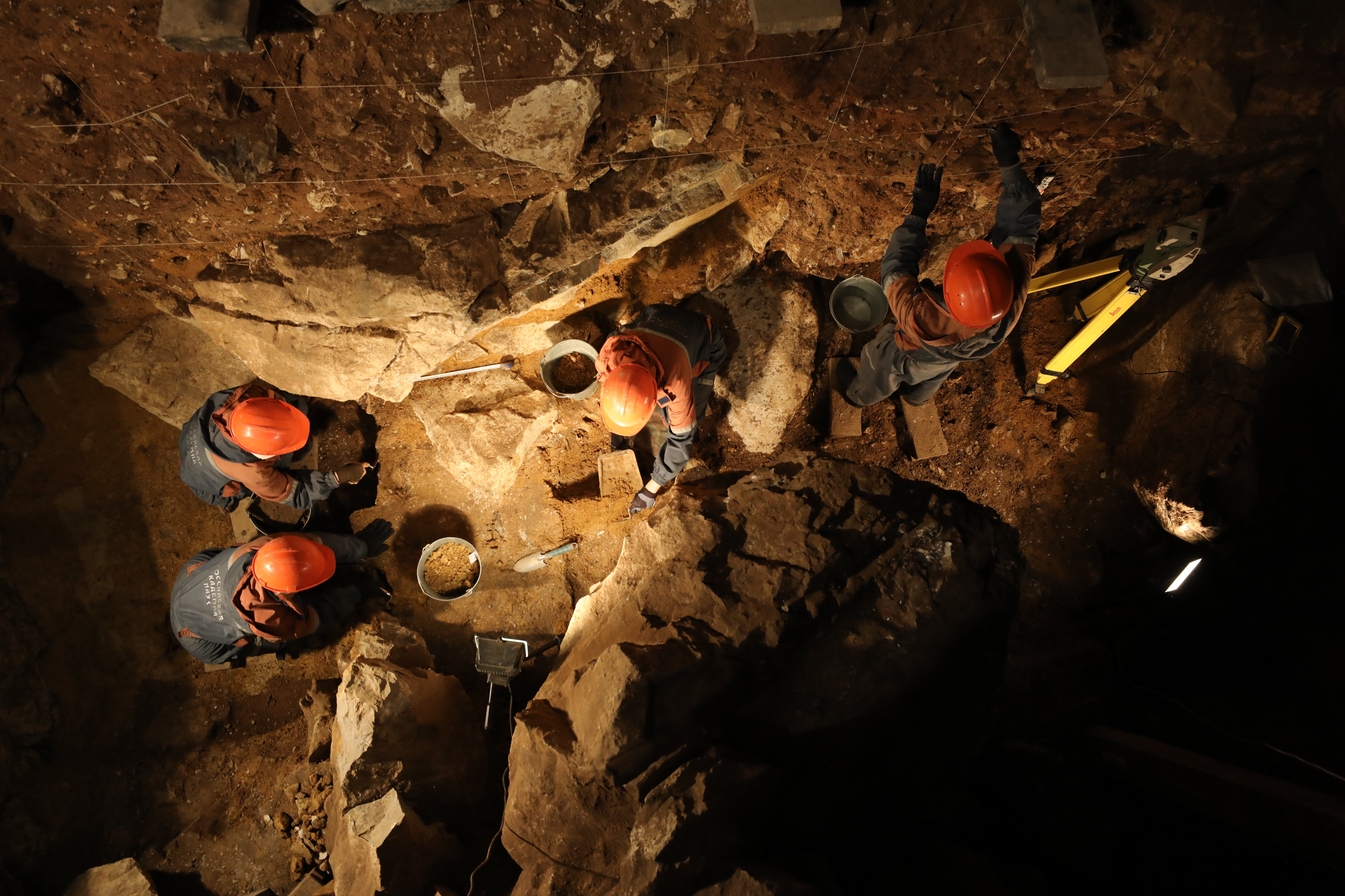scientists wearing helmets digging in a cave
