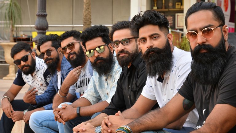 Indian men with beards sit on bench and look at camera.